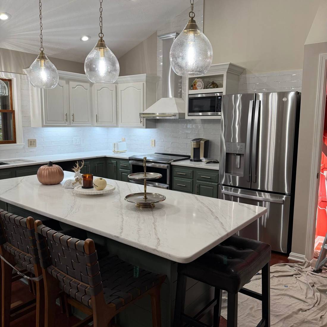 A contemporary kitchen featuring a large marble island, stainless steel appliances, and pendant lighting.